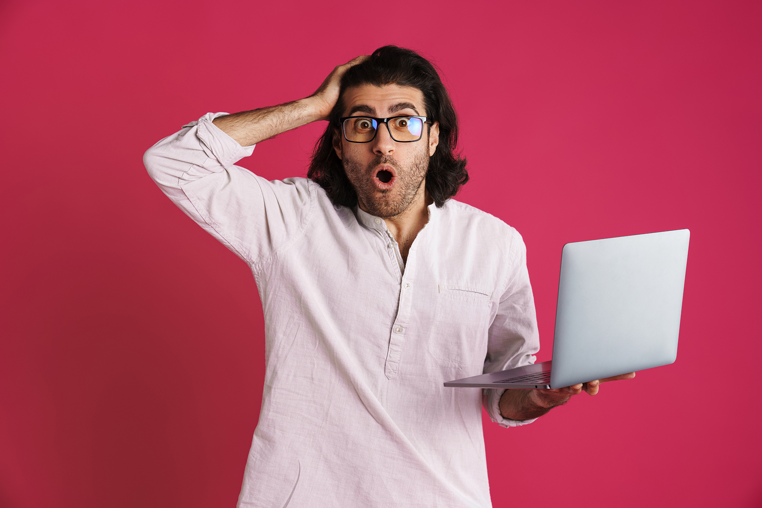 A shocked man looking at a laptop learning about the best website builders in 2025.